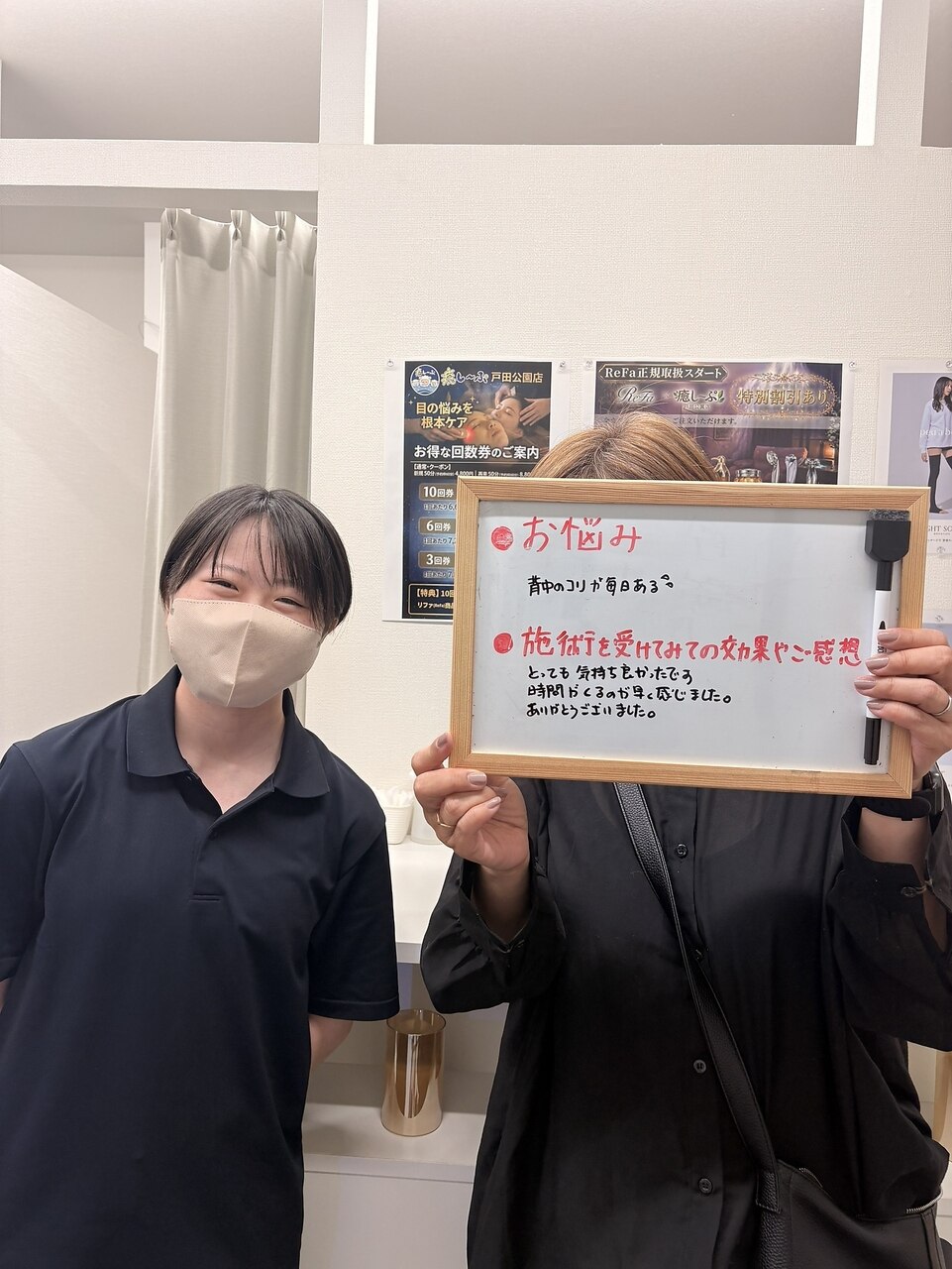 背中のこりについて感想ボードを持つお客様とスタッフ