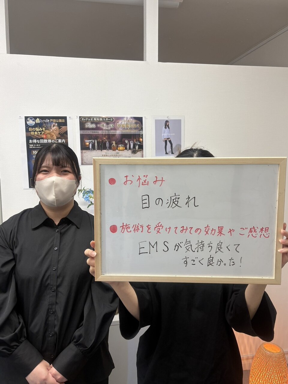 目の疲れとEMSについて感想ボードを持つお客様とスタッフ